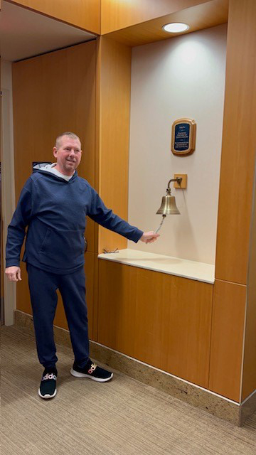 Picture of Ken ringing the bell at the hospital after fighting cancer and winning