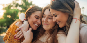 Three women are hugging and encouraging their friend. She is grateful