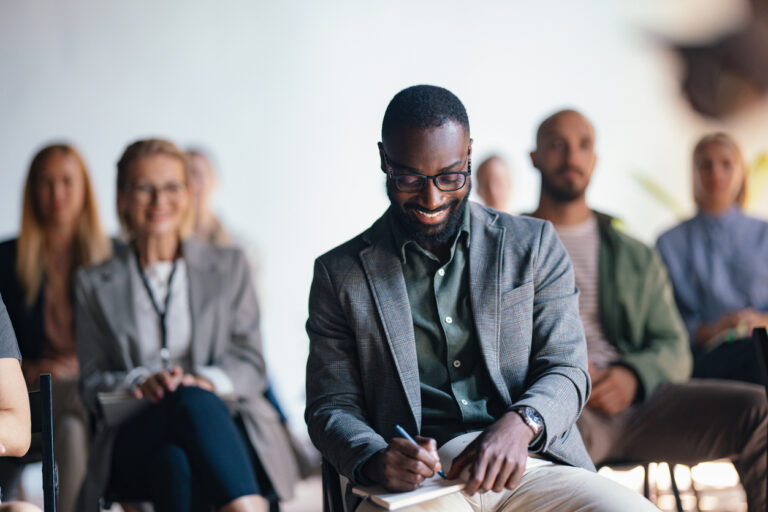 Smiling Businessman Taking Notes at Corporate Event